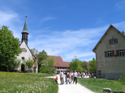 Das Freilichtmuseum Neuhausen ob Eck mit historischen Gebäuden wie z. B. einer Kirche und eines alten Wohngebäudes. Im Vordergrund des Bildes sind Besucher beim Rundgang auf dem Freigelände zu sehen (@ Freilichtmuseum Neuhausen ob Eck)