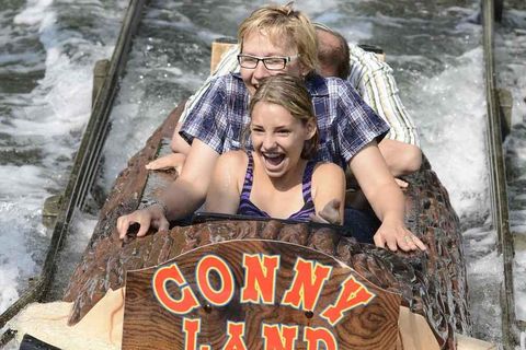 Ein Mädchen und eine Frau fahren sitzend in einem Baumstamm die Wildwasserbahn im Conny-Land